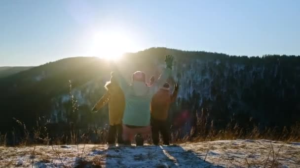 İki oğlu olan genç bir anne gün batımında bir dağın tepesinde sevinçle ellerini kaldırır.. — Stok video