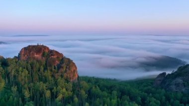 Şafak vakti siste kayalık bir zirvenin hava hızında düşüşü.