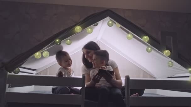 Una joven madre feliz y sus hijos están usando un teléfono inteligente. — Vídeo de stock