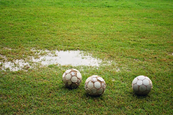 Palloni da calcio su un campo umido — Foto Stock