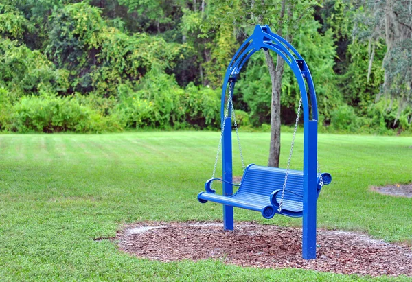 En blå gunga bänk i en park. — Stockfoto
