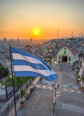 Guayaquil, Guayas, Ecuador - November, 2013: Vertical view from the lighthouse at the top of the Saint Ana hill, with a chapel and the Province's flag waving in the wind. Warm sunset. 