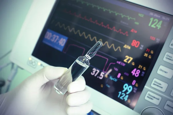 Medicamento en la mano ante el monitor médico. Concepto médico . — Foto de Stock