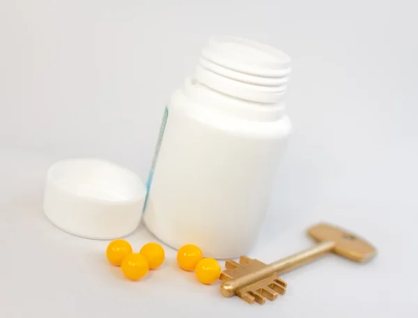 Yellow pills, and the key against the backdrop of a plastic cont — Stock Photo, Image