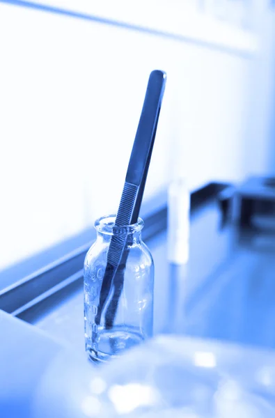 Tweezers in a glass jar at the ambulance table. — Stock Photo, Image