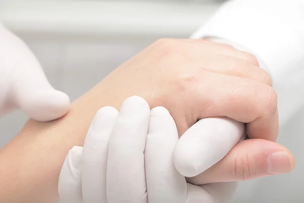 Doctor in de witte handschoenen houdt voorzichtig van de patiënt arm — Stockfoto