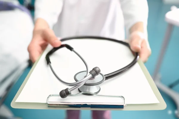 Hands of the doctor with a clipboard and a stethoscope. Humorous — Stock Photo, Image