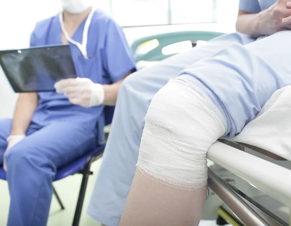 Paciente con una lesión en la rodilla y el médico con radiografía en las manos — Foto de Stock