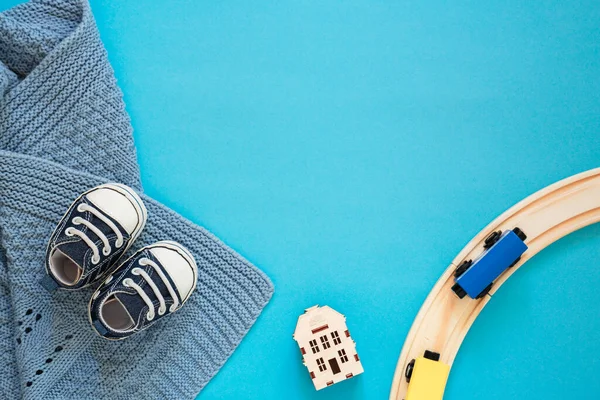 Mavi arka planda bebek ayakkabıları ve bebek oyuncakları olan bir düzen. Oğul için şirin bebek aksesuarları, mesaj için yer, tasarım için model.