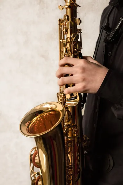 saxophonist holding alto saxophone, hands on the keys of the instrument, jazzman, learning to play the saxophone, music background