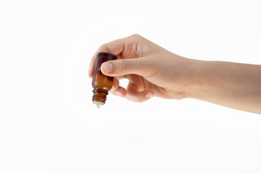 Kadın eli beyaz arka planda bir damlatıcıyla cam şişeyi tutuyor, sıvı, öz, yağ, koyu bir şişede, uyuşturucu ya da kozmetik madde konsepti