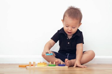 2 yaşında bir çocuk yerde oturup tahta bloklarla oynuyor.