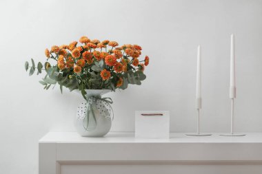 Vazoda çiçekler, mumlar ve mesaj için boş bir kart, doğum günü için bir buket portakal kasımpatı, anneler günü, yıldönümü