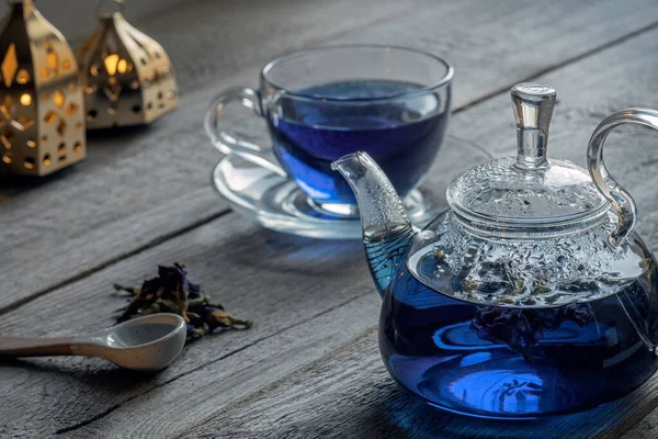 Organic Anchan blue tea, Clitoria, Butterfly tea in a glass teapot and a cup on an old wooden table, dry clitoria petals