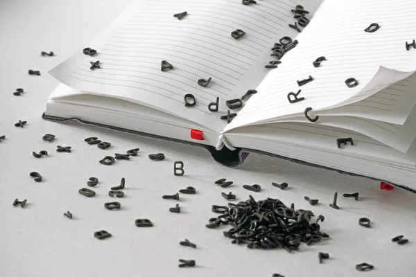 Czarne Litery Wylewają Się Pustych Stron Książki Białym Stole Edukacji — Zdjęcie stockowe