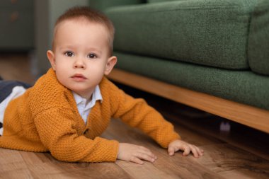 2 yaşında bir çocuk evde yerde yatıyor, oyuncaklarını çıkarıyor ve bir tasarımcı arıyor.