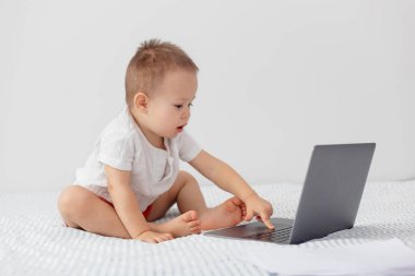 2 yaşındaki bir çocuk dizüstü bilgisayar kullanır, ekrana bakar, klavyede yazı yazar, çocukluktan itibaren sanal iletişim kavramı