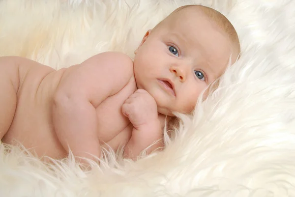 Pasgeboren baby liggend op een schapenvacht en geconfronteerd met de camera — Stockfoto