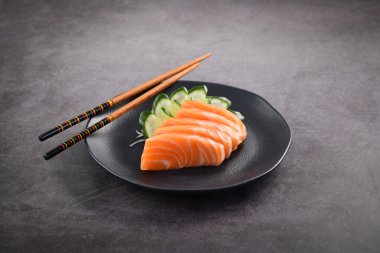 Koyu tabakta taze somon balığı dilimleri. Stüdyo çekimi arka planda.