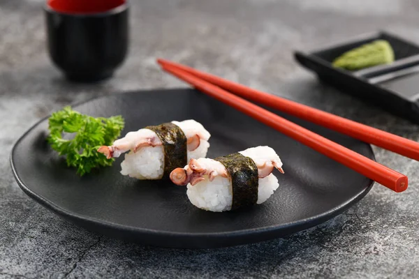 Ahtapot nigiri çifti kara tabakta. Stüdyo çekimi. Ürün resmine kapat.