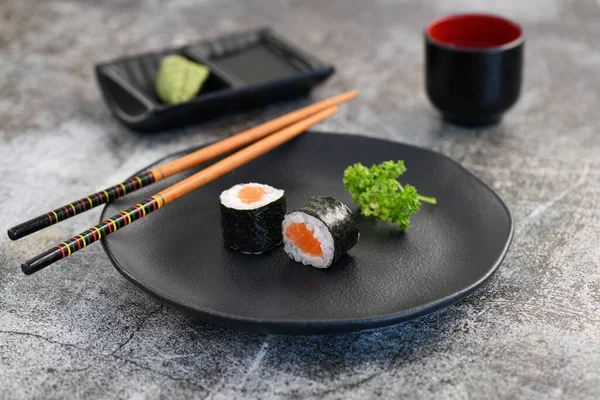 Ossomaki. Siyah tabakta somon suşisi. Stüdyo çekimi.