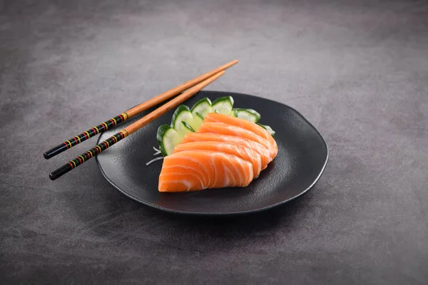 Koyu tabakta taze somon balığı dilimleri. Stüdyo çekimi arka planda.