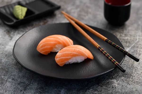 Somon Nigiri Sushi çifti siyah tabakta servis ediliyor..