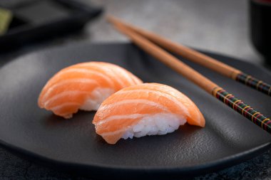 Somon nigiri çifti koyu tabakta. Balık dokusuna yakın.