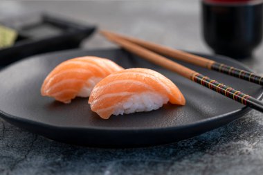 Somon nigiri çifti koyu tabakta. Balık dokusuna yakın.