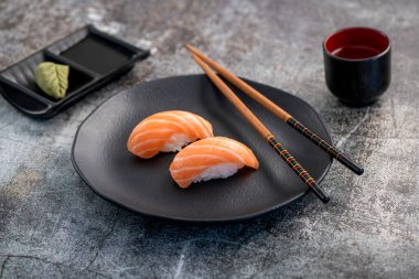 Somon nigiri çifti koyu tabakta. Balık dokusuna yakın.