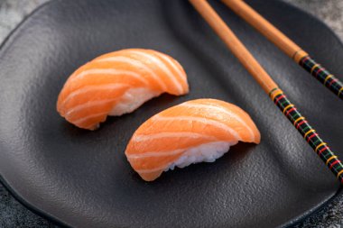 Somon nigiri çifti koyu tabakta. Balık dokusuna yakın.