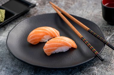 Somon nigiri çifti koyu tabakta. Balık dokusuna yakın.