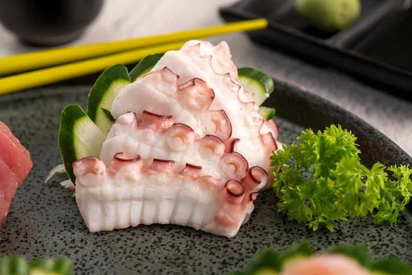 Ahtapot saşimi siyah tabakta dilimler. Stüdyo çekimi arka planda. Dokuyu kapat!