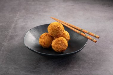 Kızarmış somon topları. Lezzetli aperatifler siyah tabakta servis edilir. Stüdyo arka planda is.
