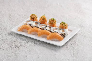 Taze suşi karışımı. Beyaz tabakta servis edilen farklı somon suşisi çeşitleri. Kapalı arkaplanda stüdyo çekimi.