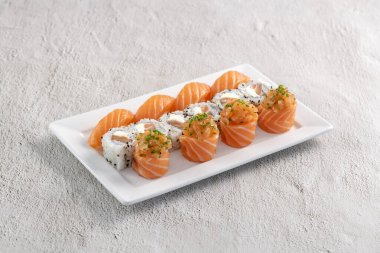 Taze suşi karışımı. Beyaz tabakta servis edilen farklı somon suşisi çeşitleri. Kapalı arkaplanda stüdyo çekimi.