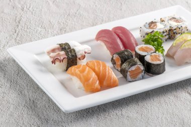Beyaz tabakta suşi karışımı. Stüdyo çekimi arka planda izole edildi. Somon, ton balığı, ahtapot ve farklı türde suşi. Brezilya usulü doğu yemekleri.!