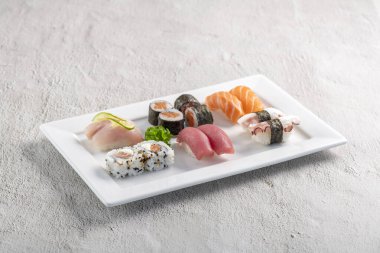 Beyaz tabakta suşi karışımı. Stüdyo çekimi arka planda izole edildi. Somon, ton balığı, ahtapot ve farklı türde suşi. Brezilya usulü doğu yemekleri.!
