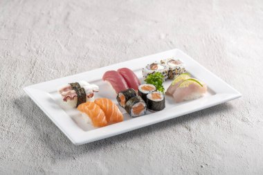 Beyaz tabakta suşi karışımı. Stüdyo çekimi arka planda izole edildi. Somon, ton balığı, ahtapot ve farklı türde suşi. Brezilya usulü doğu yemekleri.!