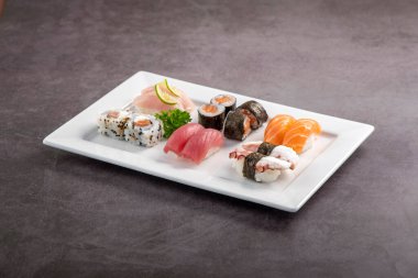 Beyaz tabakta suşi karışımı. Stüdyo çekimi arka planda izole edildi. Somon, ton balığı, ahtapot ve farklı türde suşi. Brezilya usulü doğu yemekleri.!
