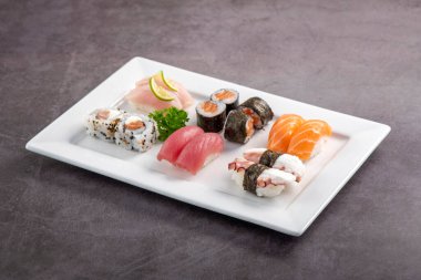 Beyaz tabakta suşi karışımı. Stüdyo çekimi arka planda izole edildi. Somon, ton balığı, ahtapot ve farklı türde suşi. Brezilya usulü doğu yemekleri.!
