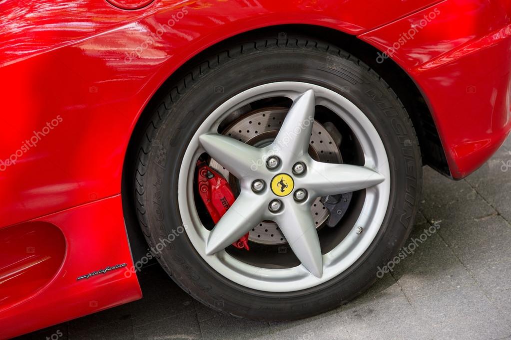 Rear wheel details of beautiful bright red Ferrari sport car parked on the city street