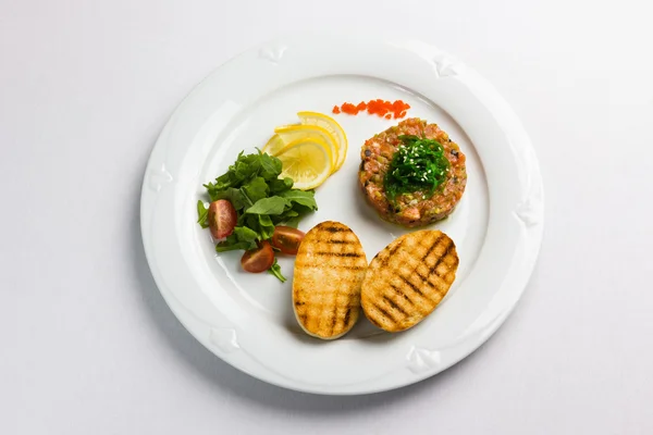 Fish tartare with vegetables and crackers — Stock Photo, Image