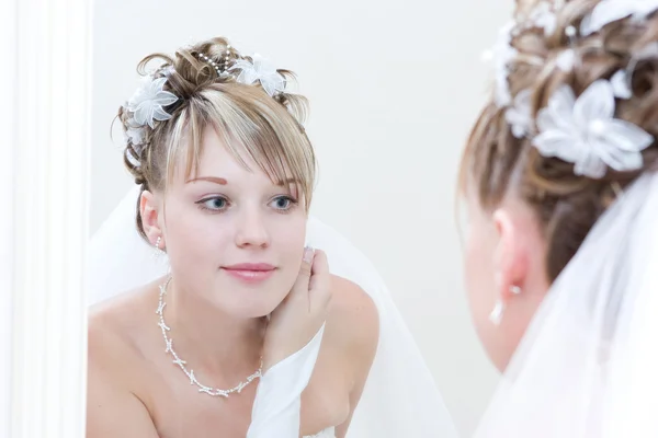 Jeune mariée regarde dans un grand miroir — Photo