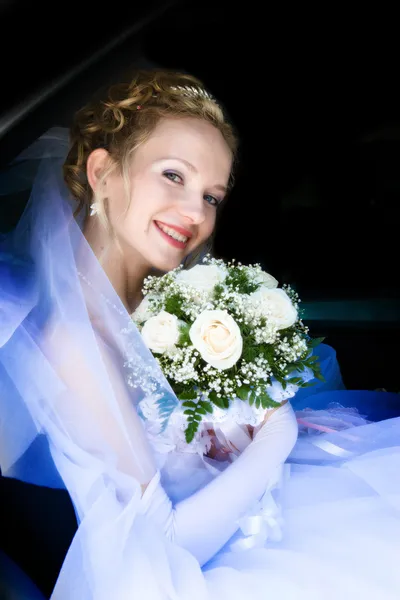 Bride with a flower bouquet in a car — Stock Photo, Image