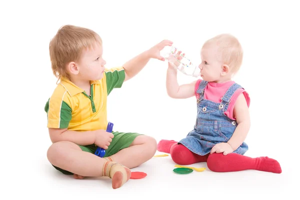 Un niño pequeño dando de beber junto a la botella a la niña pequeña — Foto de Stock