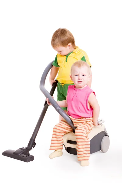 Uma menina pequena e um menino pequeno pelo aspirador — Fotografia de Stock