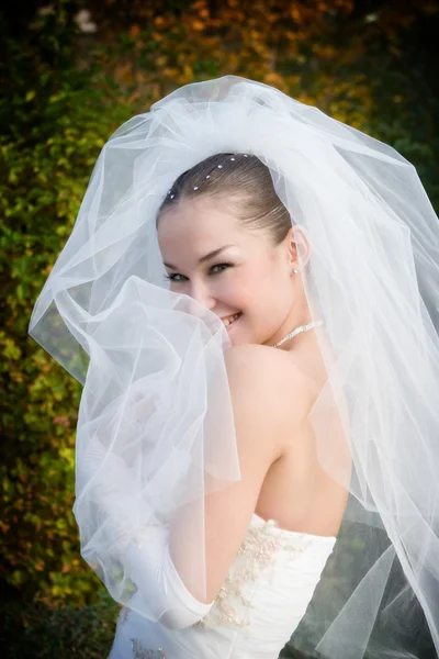 Een lachende bruid verbergt in haar sluier — Stockfoto