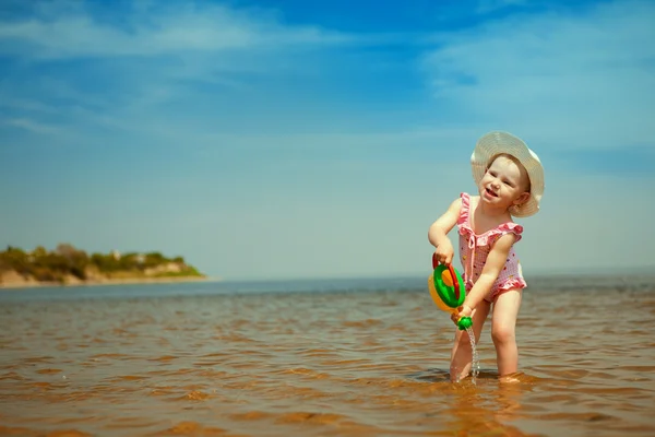 Kind met drenken-pot op de kust — Stockfoto