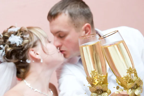 Kissing Newly-married couple with full glasses of a champagne — Stock Photo, Image